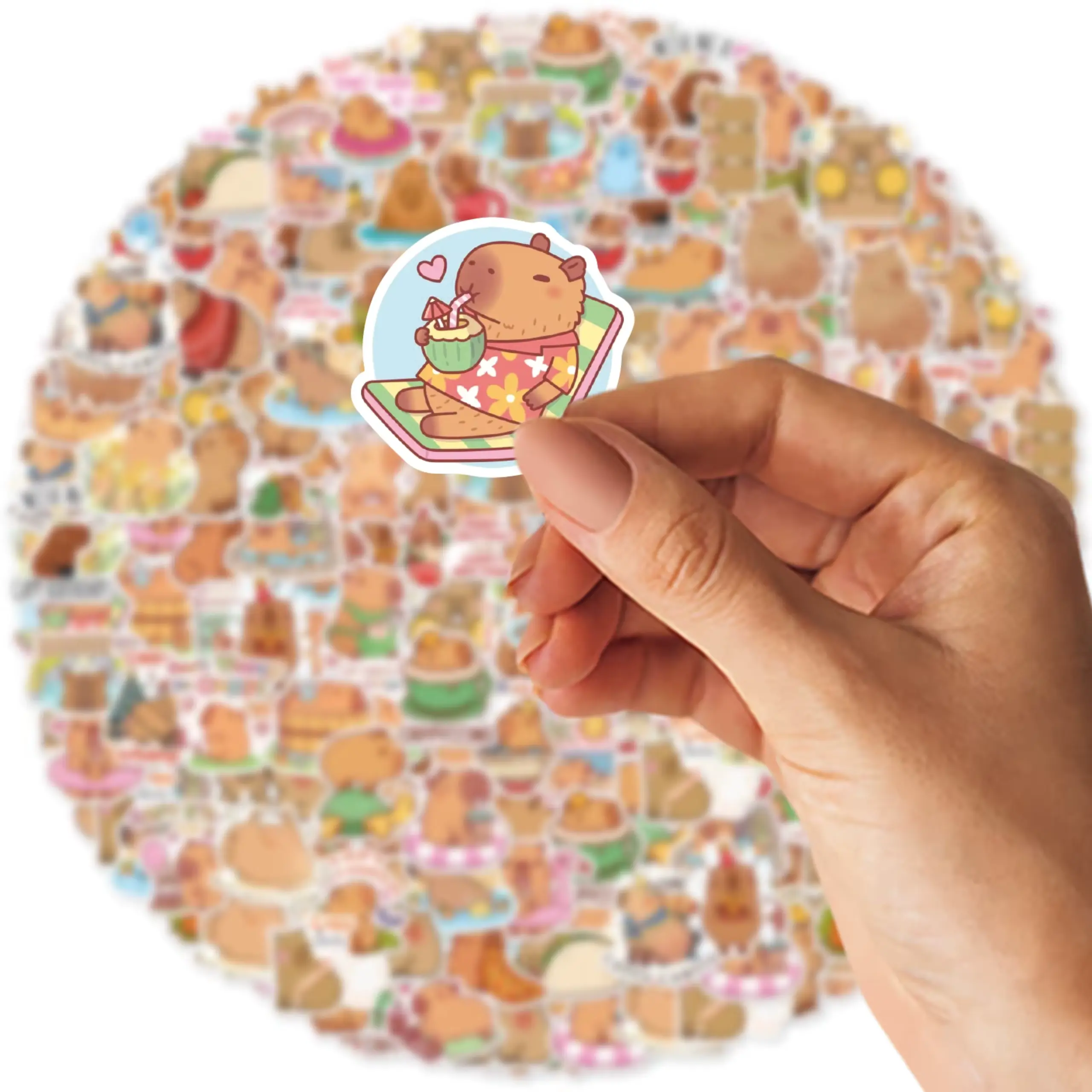 Dłoń trzyma małą, uroczą naklejkę z kapibarą relaksującą się w drewnianej balii z gumową kaczuszką; w tle rozmyta kolekcja podobnych naklejek z kapibarami